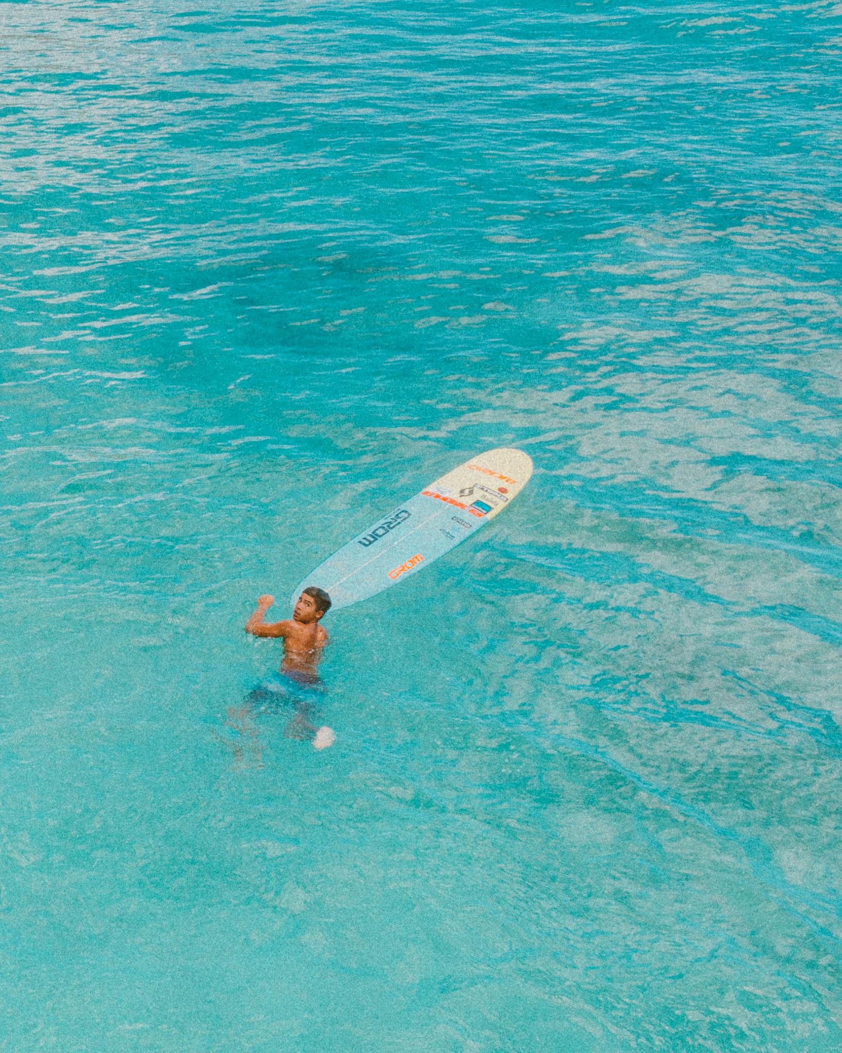 Aerial photo of a surfer floating in clear Hawaiian waters.