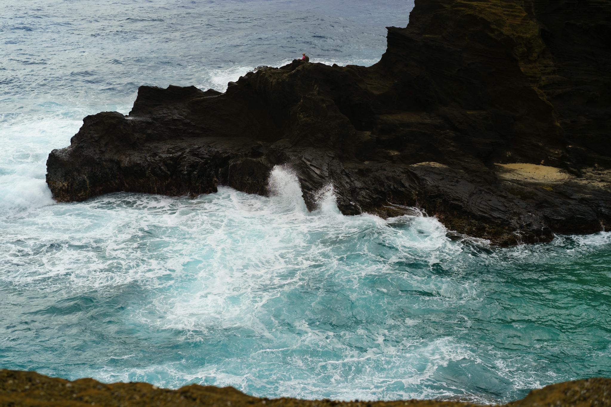 Powerful waves crash against rugged cliffs, creating a scenic and dramatic seascape.